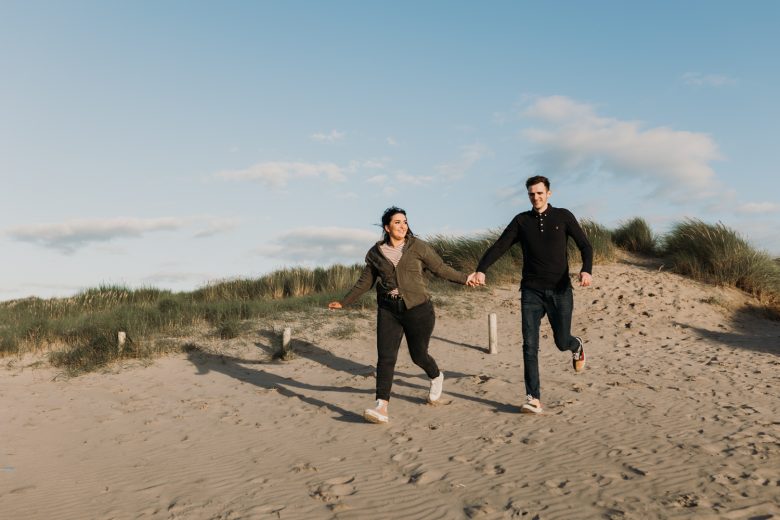 couple running down a sand dune
