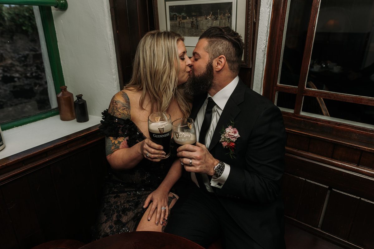 bride and groom in Irish pub kissing with pints of Guinness in hand