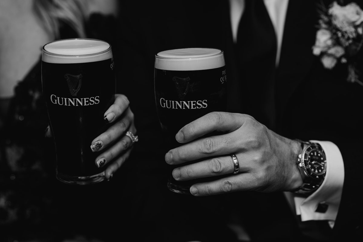 close up of two pints of Guinness held by bride and groom in Irish pub