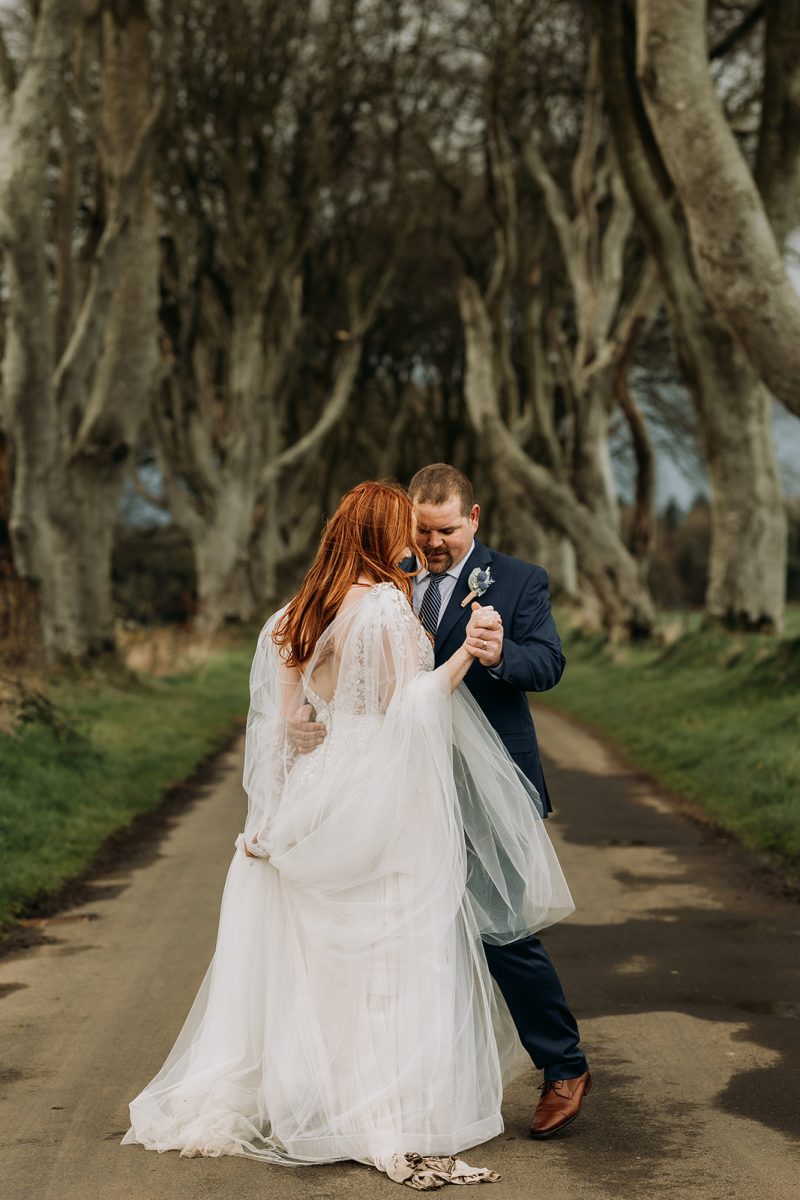 eloping bride and groom at the Dark Hedges dancing together