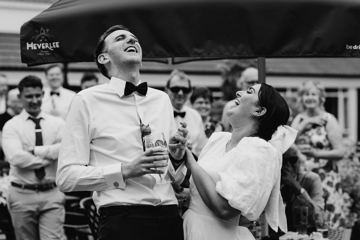 bride and groom bent over laughing together