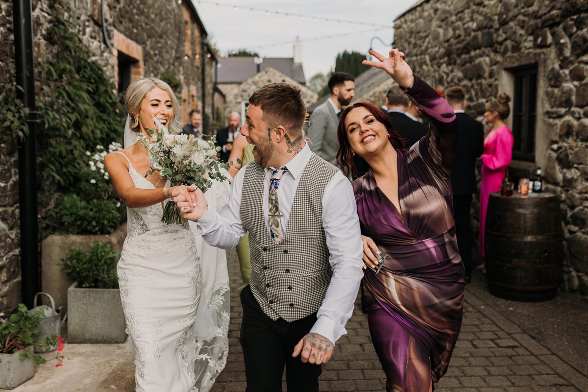 bride with a female and male friend walking towards the camera ready for a party