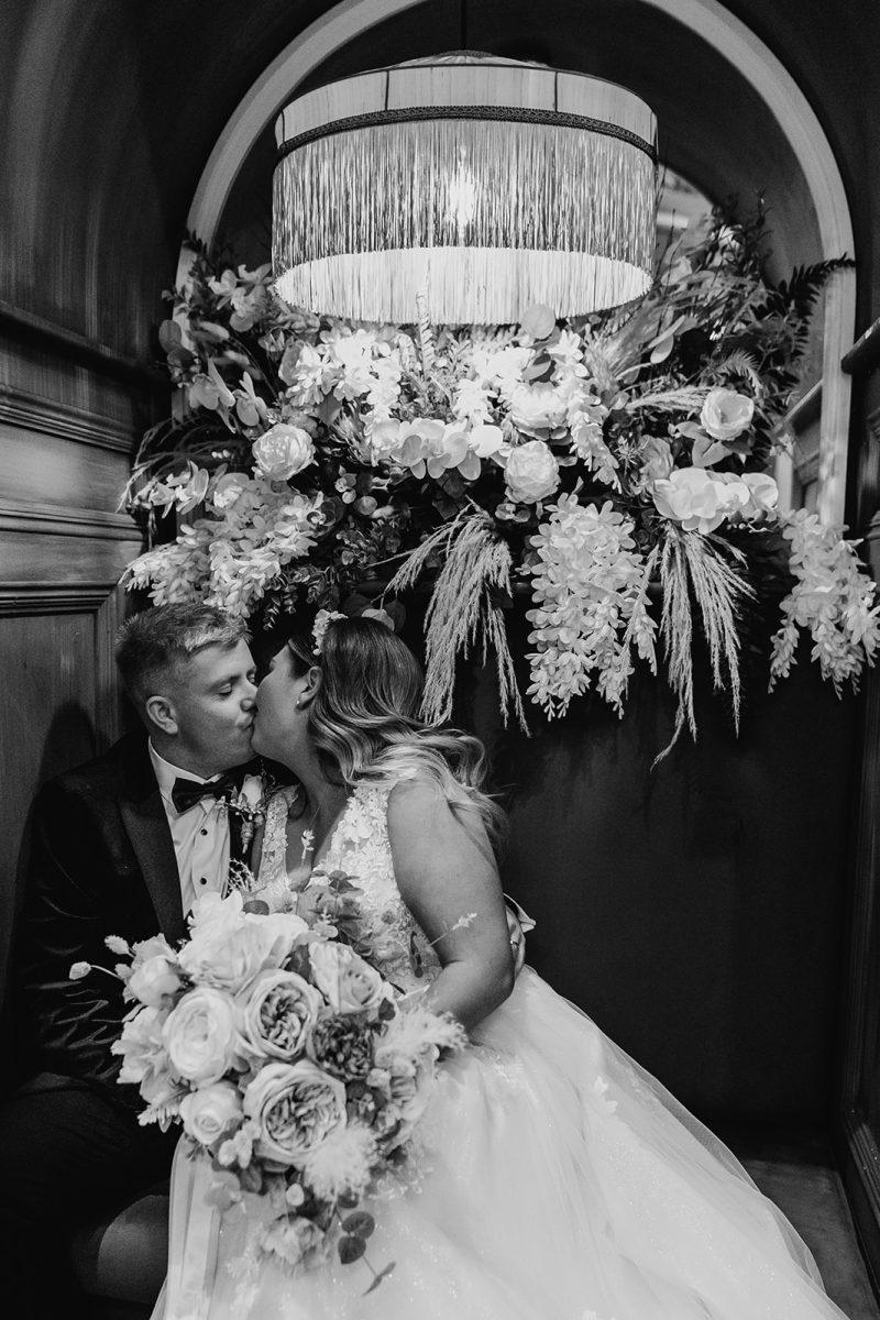 bride and groom kissing in cosy seating area at the Loft.