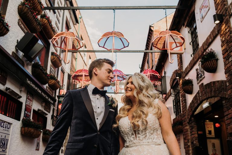 bride and groom standing under the Belfast umbrellas outside the Duke of York pub in Belfast city center.
