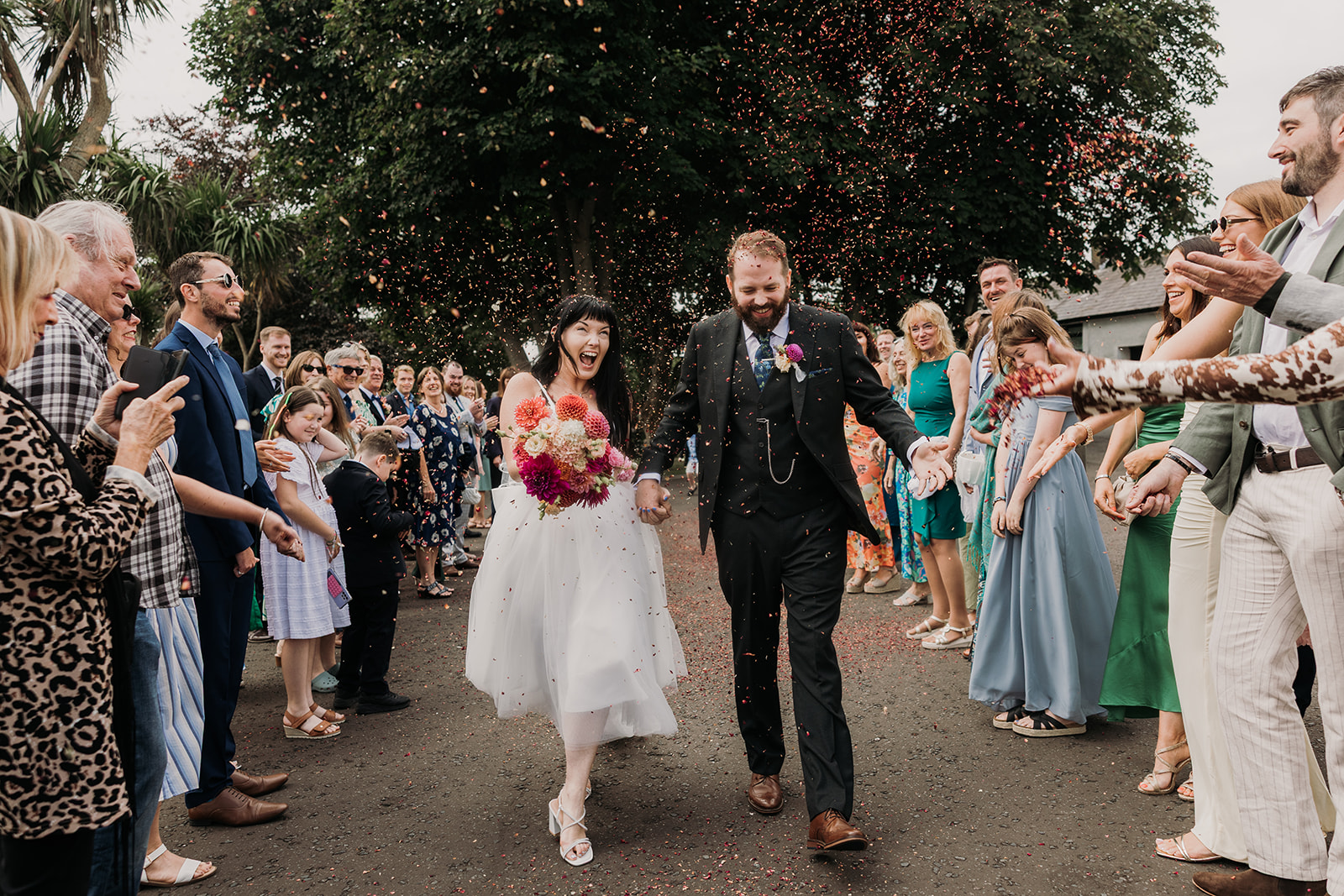 bride and groom on wedding day having confetti thrown at them.