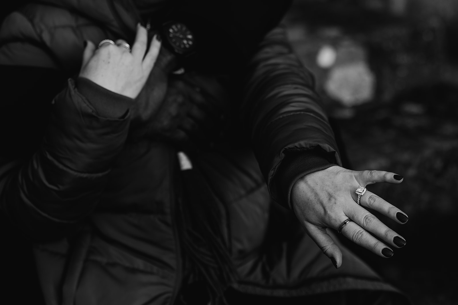 close up of couples hands who are embracing. Shows engagement ring on finger.
