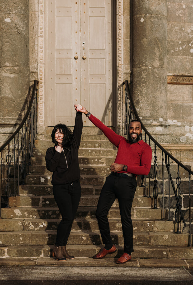 couple with hands in the air as she just said yes to being engaged.