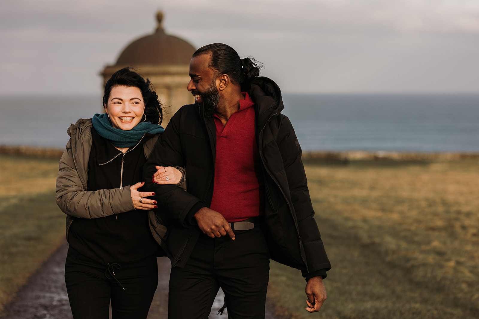 couple walking together with Mussenden temple in background